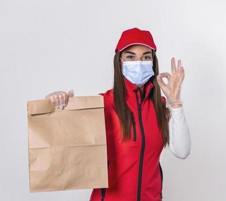 delivery-woman-in-red-uniform-hold-craft-paper-packet-with-food-isolated-on-white-background-wearing-medical-mask-and-gloves-female-employee-i-working-as-courier-service-concept-photo